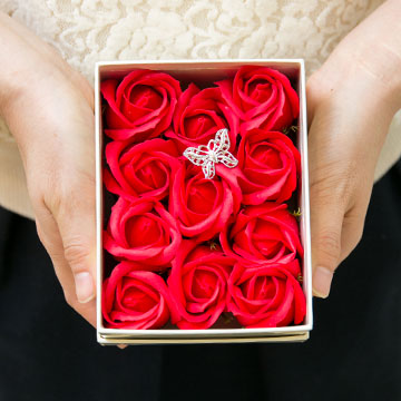 バラのソープフラワーを持つ女性の手